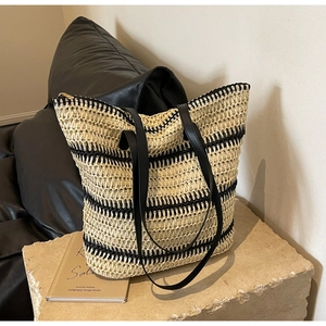 Détail d'un grand sac cabas tissé avec rayures noires sur un socle en pierre