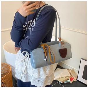 Détail du sac baguette bleu clair avec pendentif cœur et franges dans un décor intérieur