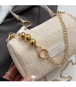 Detail of woven beige barrel bag showing golden chain and leather logo patch texture