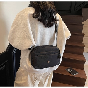 Détail du sac bandoulière en nylon noir avec poches multiples et sangle à motifs