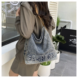 Detail view of denim tote bag with FASHION lettering and soft brown fabric straps