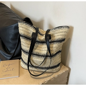 Détail de la texture du sac cabas en paille tressée et des anses en similicuir noir