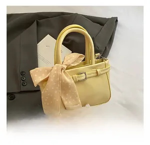 Detail of yellow faux leather square bag featuring lychee texture and polka dot silk ribbon