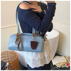 Détail du sac baguette bleu clair avec texture vintage et breloque à franges en intérieur