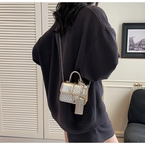 Detail of metallic gold mini crossbody bag with woven texture and chain strap on model