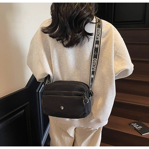 Détail du sac bandoulière noir avec poches zippées et bandoulière large à motifs géométriques