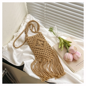Close-up of khaki woven crossbody bag featuring knot texture and long decorative fringe