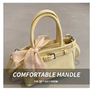 Close-up of yellow leather handbag with round handles and decorative polka dot scarf