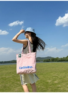 Sac cabas en nylon rose avec imprimé LanShaWan bleu porté par un mannequin en extérieur