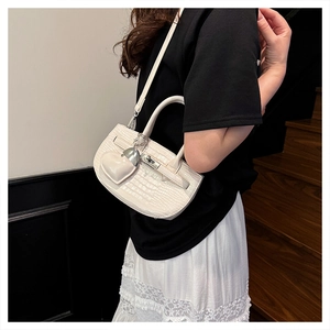 Detail of white crocodile embossed texture handbag with gold metal lock and heart charm