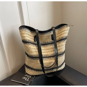 Détail d'un grand sac cabas en paille tissée avec rayures noires et poignées en cuir