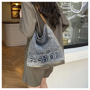 Outdoor shot of a vintage denim tote bag with embossed fashion lettering on a model