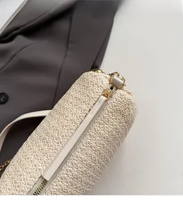 Detailed macro shot of smooth gold-tone metal zipper on woven beige straw pillow bag