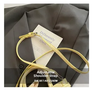 Detail of adjustable pale yellow leather shoulder strap with silver metal buckle