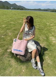 Vue extérieure d'un sac fourre-tout rose et d'une robe blanche à bordure bleue