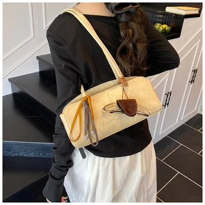 Détail d'un sac baguette minimaliste beige avec pompon élégant et lunettes de soleil en déco