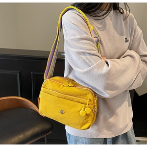 Vue détaillée du sac bandoulière en nylon jaune vif avec plusieurs poches zippées