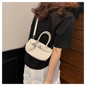 Detailed shot of beige crocodile pattern handbag with heart charm shown on model