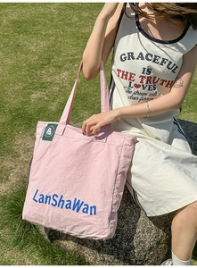 Sac cabas en nylon rose avec lettrage bleu LanShaWan et étiquette verte présenté en plein air