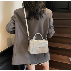Detail of silver crossbody bag with woven texture, round handle and fashion tag