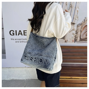 Close-up of washed blue denim tote bag with 3D embossed FASHION lettering detail