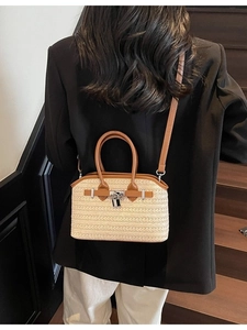 Woven straw Boston bag with brown leather handles and silver metal lock in crossbody style