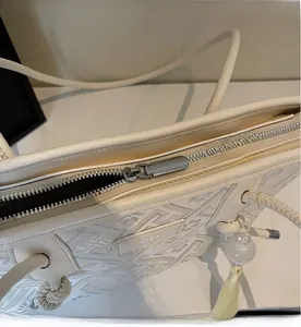 Draufsicht auf den Reißverschluss und die geometrische Stickerei der cremefarbenen Tasche