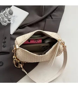Detail of cream woven shoulder bag interior with phone, wallet and gold bell charm