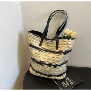 Détail macro du tissage et des anses en cuir noir sur ce sac cabas à rayures stylé