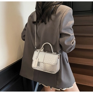 Detail showing metallic silver structured handbag with woven texture and top handle