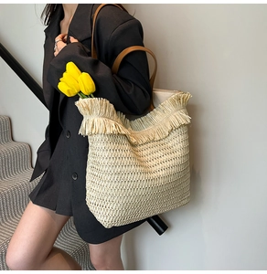 Detail der handgewebten Stroh-Tote-Bag mit Fransenkante und braunem Leder-Schultergurt