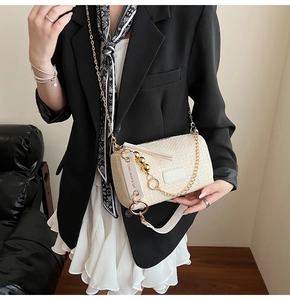 Détail du sac bandoulière tressé crème avec chaîne dorée et étiquette de marque en cuir