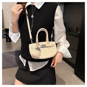 Detail of cream faux crocodile texture handbag with silver twist lock and heart charm