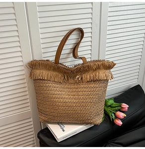 Detailaufnahme der Stroh-Tasche mit Fransenbesatz und braunen Ledergriffen im Display