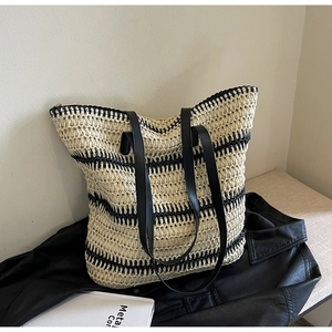 Vue détaillée du sac cabas en paille tissée avec rayures noires et anses en cuir noir
