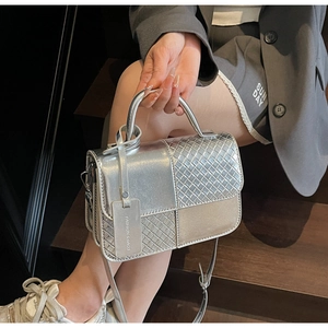Close-up of silver crossbody bag featuring woven texture and metallic curved handle
