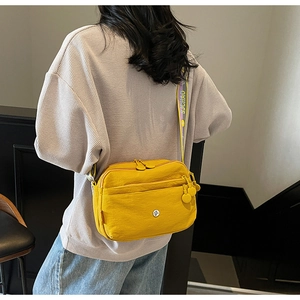 Vue détaillée du sac bandoulière jaune vif avec large sangle logotypée et double fermeture