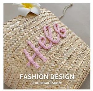 Detail der handgewebten Strohtasche mit rosa 3D-Hello-Stickerei für den Sommerurlaub