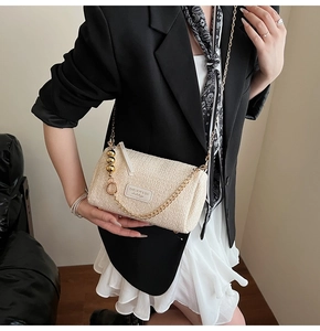 Détail du sac polochon en polaire beige avec chaîne dorée et écusson en cuir de marque