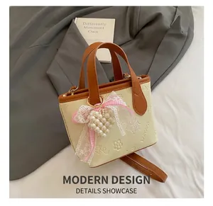 Close-up of beige butterfly bucket bag with pearl heart charm and lace bow details