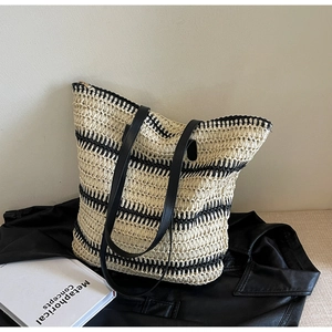 Détail d'un sac cabas tissé avec rayures noires et poignées en cuir durables