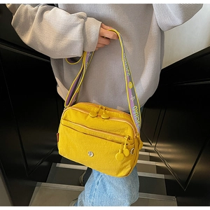 Détail de la sacoche en nylon jaune vif à plusieurs poches et bandoulière lettrée
