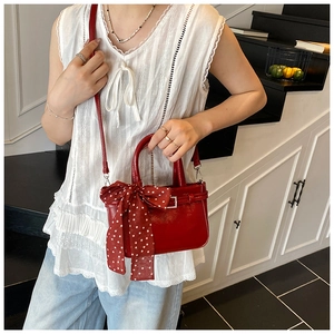 Detail of red patent leather handbag with polka dot bow and silver hardware
