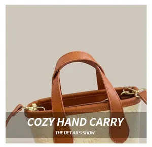 Close-up of cream bucket bag with brown leather handles and gold zipper detail