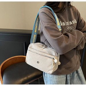 Détail du sac bandoulière en nylon gris avec poches zippées et bandoulière jacquard