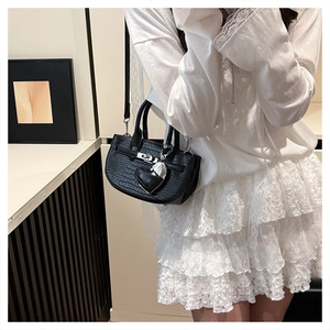 Close-up of black crocodile pattern mini handbag with silver lock and heart charm