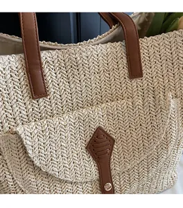Close-up of woven straw tote bag featuring beige wave texture and brown leather flap pocket