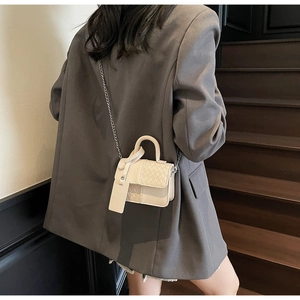 Close-up of a beige mini crossbody bag with woven texture and a circular metal handle