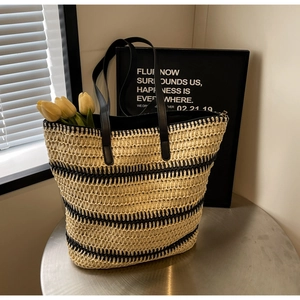Gros plan d'un sac cabas tissé rayé avec anses en cuir et tulipes sur une table