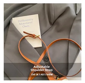 Detail showing adjustable brown leather shoulder strap with high-quality gold metal buckle